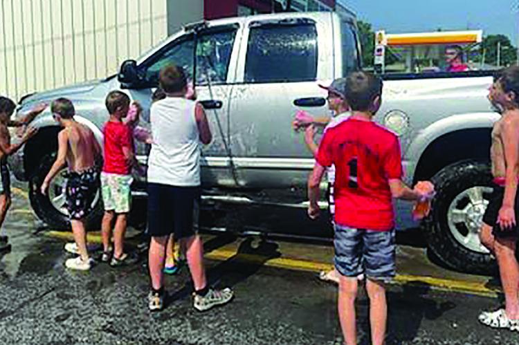 IMPACT baseball boys get wet in their swim trunks as they wash a truck for a good cause.