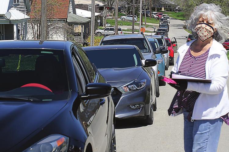 VOLUNTEER Eleanor Covey goes to each vehicle along North Shaw Street to ask about the number of people the driver plans to help. Whether for one person or several families, Harvesters helps out.