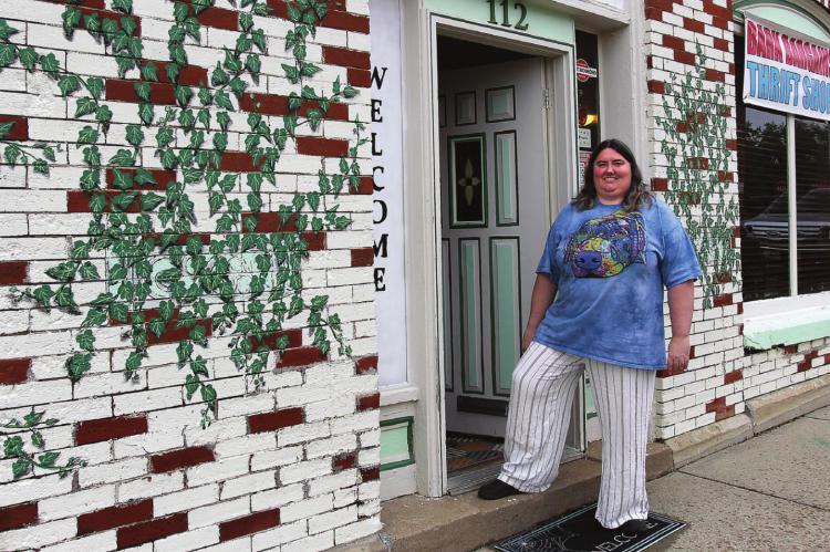 JENIFER DICKSON stands in the doorway of Bark Bargains, 112 S. College St., Richmond. The storefront is designed to catch the eye with the bricks painted white and red, and the leaves painted over bricks.
