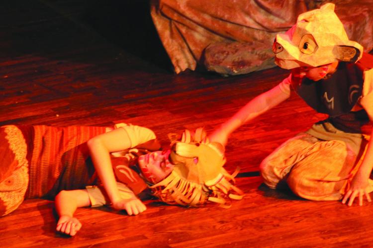 SIMEON DURHAM (left) plays Mufasa lying on the floor and Elijah Durham plays young Simba mourning the loss of his father.