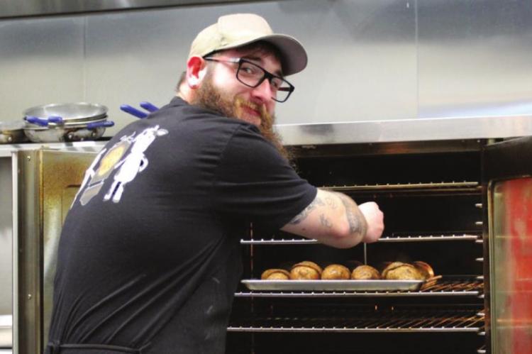 OPENING THE OVEN in Branded Steakhouse’s spacious kitchen, Jacob O’Dell tends potatoes baking for the lunch crowd.