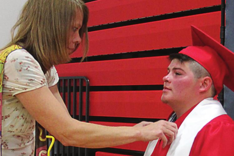 IN PREPARATION for a portrait photo, Kathy Troxel helps son Ryan Graham with his graduation garments.