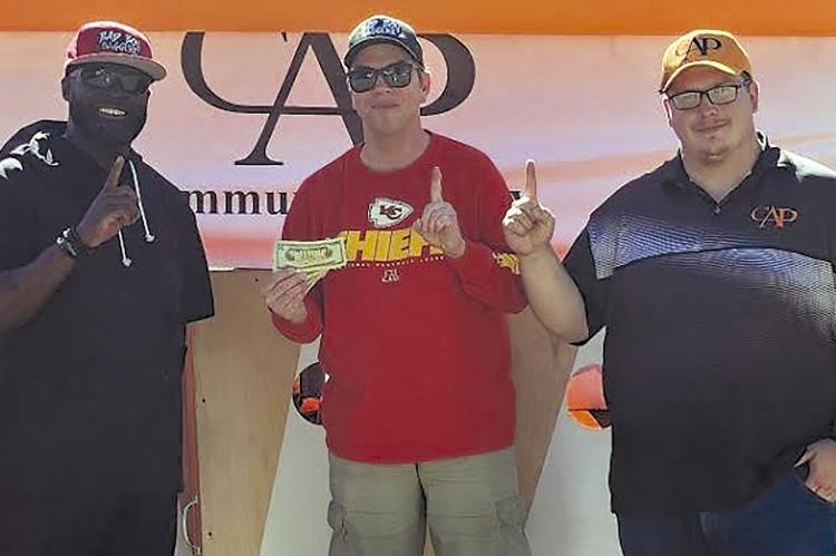 TODD MCCANT (from left) and Chris Battagler win first place at the Community at Play’s (CAP) Lawson Cornhole Tournament. CAP Implenter Alexander Hays provided the winner’s prize. Submitted